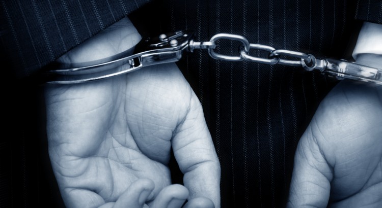 Concept of hands of business man in handcuffs showing business crime.