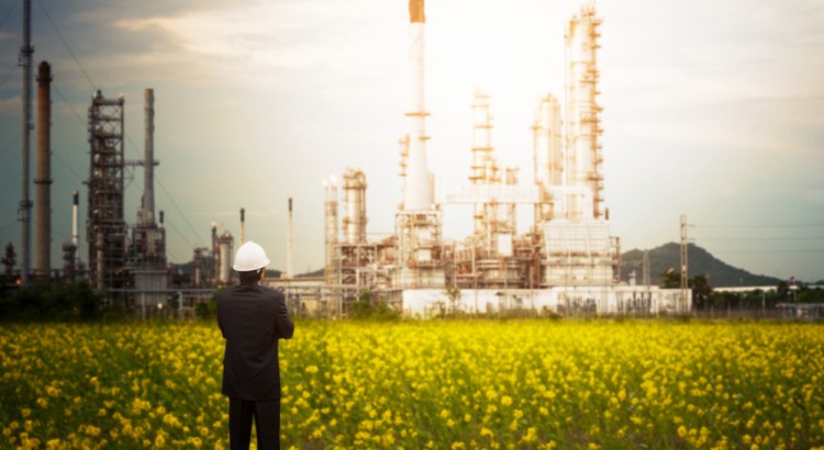 Male oil executive looks out at oil plant.